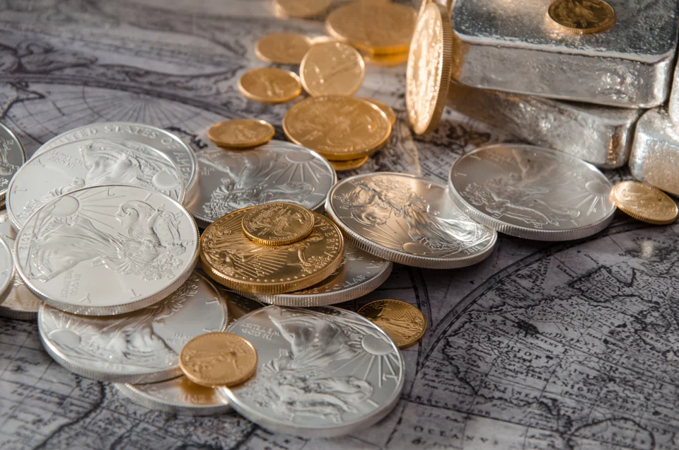 American Gold and Silver Eagles spilling from a stack of cast silver bars over an antique map