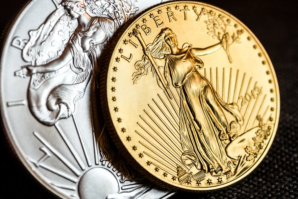 Close view of an American Gold Eagle beside an American Silver Eagle